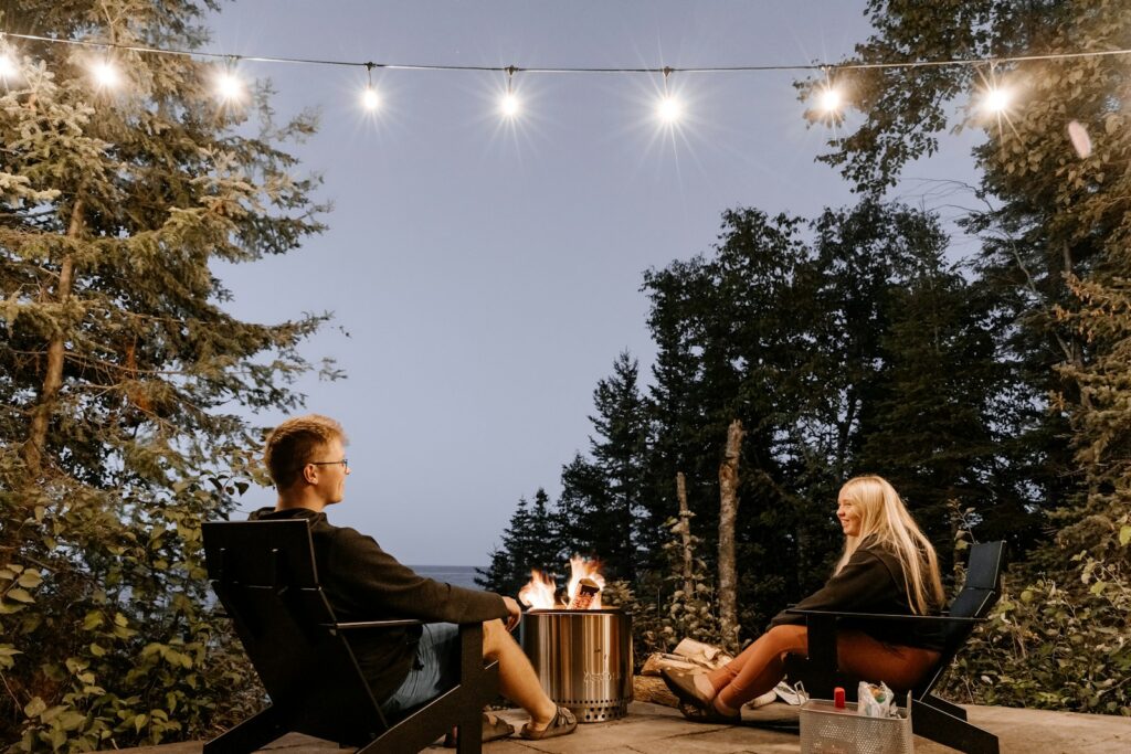 a man and a woman sitting at a table with a fire pit