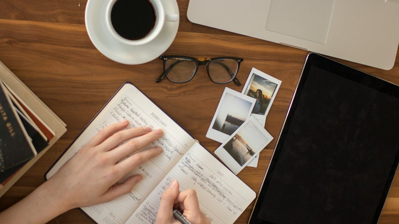 person holding ballpoint pen writing on notebook